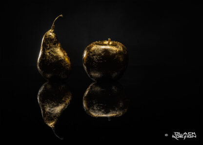Foto på guldförgylld frukt, päron och äpple mot svart bakgrund. 100x70 beskärning.