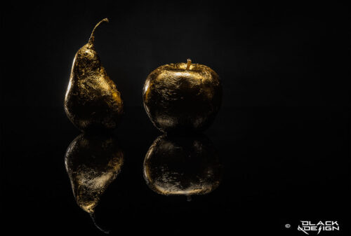 Foto på guldförgylld frukt, päron och äpple mot svart bakgrund. 100x70 beskärning.