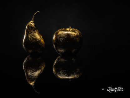 Foto på guldförgylld frukt, päron och äpple mot svart bakgrund. 40x30 beskärning.