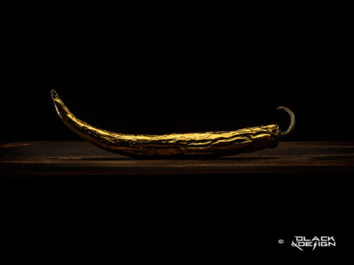 golden-chili - foto på en guldförgylld chilli mot svart bakgrund.